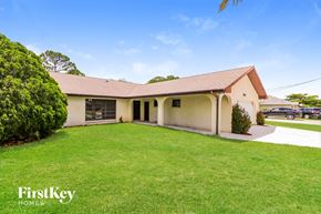 Port St. Lucie house for rent - a white house with a green lawn and a driveway