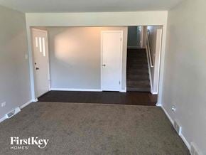 Dolton house for rent - a empty living room with a carpeted floor and a staircase