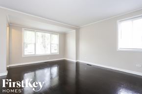 Dolton house for rent - a clean and empty room with black resin flooring and two windows