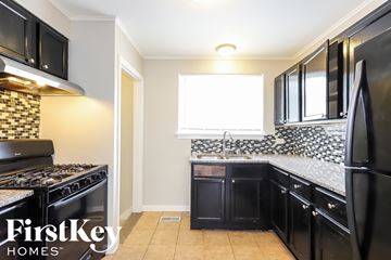 Dolton house for rent - a kitchen with black cabinets and a stove and a window