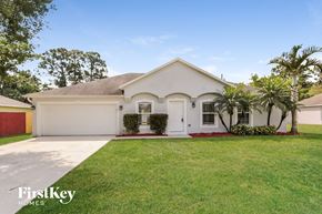 Port St. Lucie house for rent - a white house with a lawn and palm trees