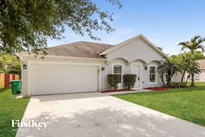 Port St. Lucie house for rent - a white house with a white garage door and a lawn