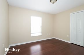 Port St. Lucie house for rent - a bedroom with wood floors and a window and a white door