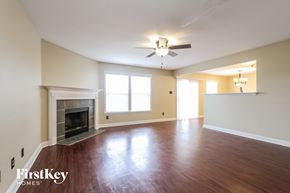 Greenwood house for rent - an empty living room with a fireplace and a ceiling fan