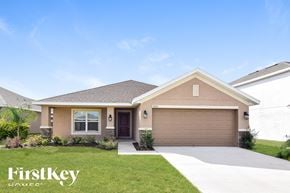 Wimauma house for rent - a beige house with a garage door and a lawn