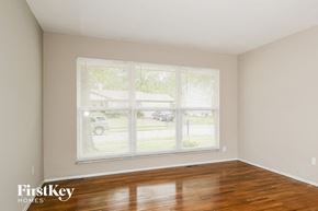 Florissant house for rent - the living room of a home with a large window and wood floors