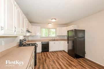 Florissant house for rent - a kitchen with white cabinets and a black refrigerator