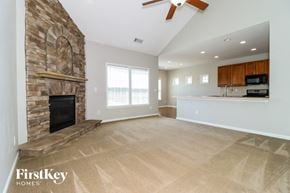 Cumming house for rent - A spacious living room with a stone fireplace and a kitchen area in the background.
