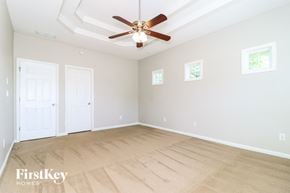 Cumming house for rent - A spacious room with a ceiling fan and light, two doors, and a window.
