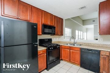 Houston house for rent - a kitchen with black appliances and wooden cabinets