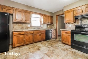 Grandview house for rent - a kitchen with wooden cabinets and black appliances