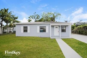 Miami house for rent - A white house with a green lawn in front of it.