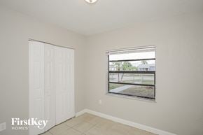 Miami house for rent - A room with a white door and a window showing a view of a building and trees.