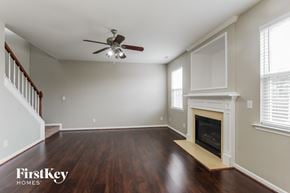 Charlotte house for rent - A spacious room with a fireplace and a ceiling fan.
