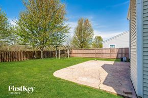 Noblesville house for rent - a backyard with a wooden fence and a patio with green grass and a house