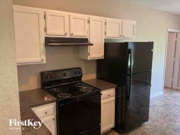 North Port house for rent - a kitchen with black appliances and white cabinets