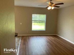 North Port house for rent - an empty living room with a ceiling fan and wood floors