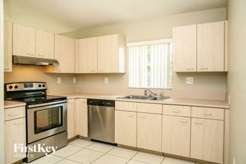 Miami house for rent - a kitchen with wooden cabinets and stainless steel appliances