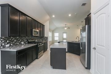 Haslet house for rent - a large kitchen with black cabinets and stainless steel appliances