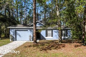 Starke house for rent - A blue house with a garage is surrounded by trees.