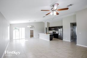 Port St. Lucie house for rent - A spacious kitchen and living room with a ceiling fan and tiled flooring.