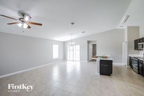Port St. Lucie house for rent - A spacious living room with a ceiling fan and a kitchen area in the background.