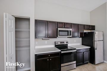Port St. Lucie house for rent - A kitchen with dark brown cabinets and stainless steel appliances.