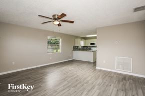 Homestead house for rent - an empty living room and kitchen with wood flooring and a ceiling fan