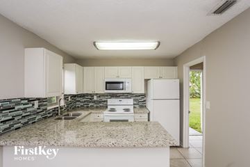 Homestead house for rent - a kitchen with white cabinets and granite counter tops and a white refrigerator