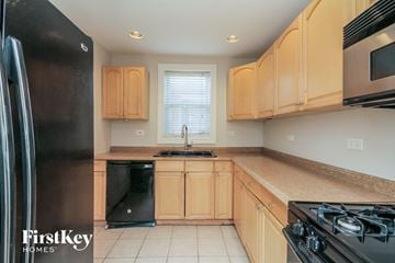 Midlothian house for rent - a kitchen with wooden cabinets and black appliances and a window