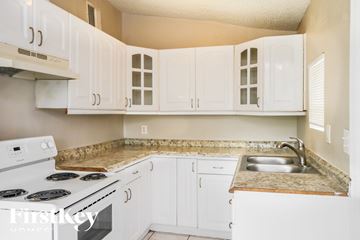 Fort Lauderdale house for rent - A kitchen with white cabinets and a stove top oven.