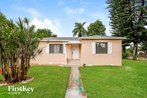 Miami house for rent - a home with a green lawn and a palm tree