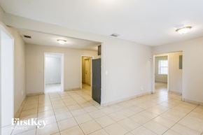 Miami house for rent - a spacious living room with tiled flooring and white walls