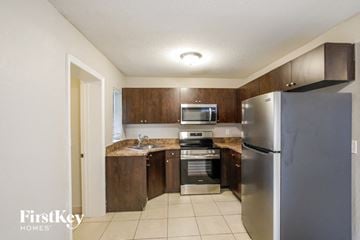 Miami house for rent - a kitchen with stainless steel appliances and wooden cabinets