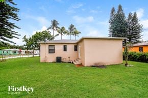 Miami house for rent - a small pink house with a grass yard and palm trees