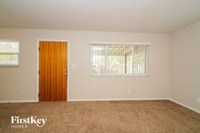 Indianapolis house for rent - A room with a brown carpet, a wooden door, and a window with blinds.