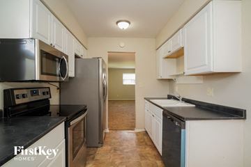 Indianapolis house for rent - A kitchen with white cabinets and black countertops.