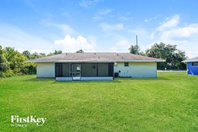 Port Charlotte house for rent - A house with a white exterior and a yellow roof is surrounded by a grassy lawn.