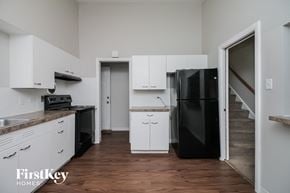 Dolton house for rent - a kitchen with white cabinets and a black refrigerator