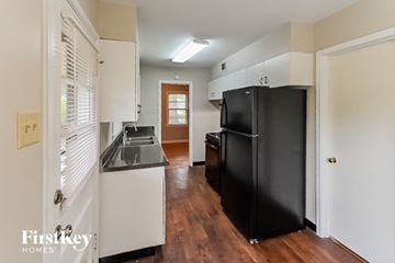 Memphis house for rent - a kitchen with a black refrigerator and a door to a hallway