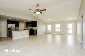 Cape Coral house for rent - an empty kitchen and living room with a ceiling fan