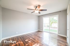 Tempe house for rent - A room with a ceiling fan and wooden floors.
