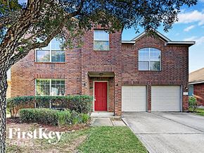 Cypress house for rent - a red brick house with a red door and white garage doors