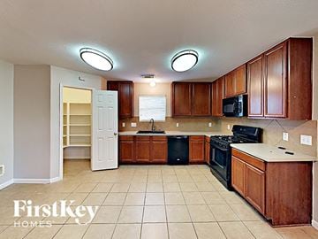 Cypress house for rent - a kitchen with wooden cabinets and a black stove