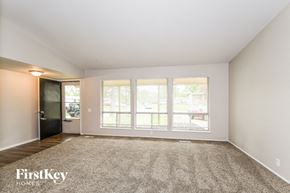 Florissant house for rent - A spacious empty room with a carpeted floor and a door leading to a balcony.