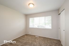 Florissant house for rent - A room with a carpeted floor and a window showing a view of trees and a building outside.
