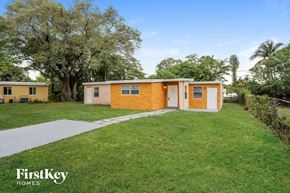 Fort Lauderdale house for rent - a small yellow house with a yard and a sidewalk