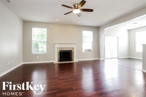 Noblesville house for rent - A spacious living room with a fireplace and a ceiling fan.