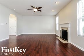 Noblesville house for rent - A spacious room with a fireplace and a ceiling fan.
