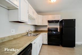 Arnold house for rent - a kitchen with white cabinets and black appliances